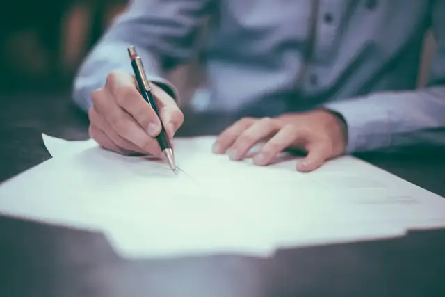 Persona organizando documentos y papeles sobre un escritorio